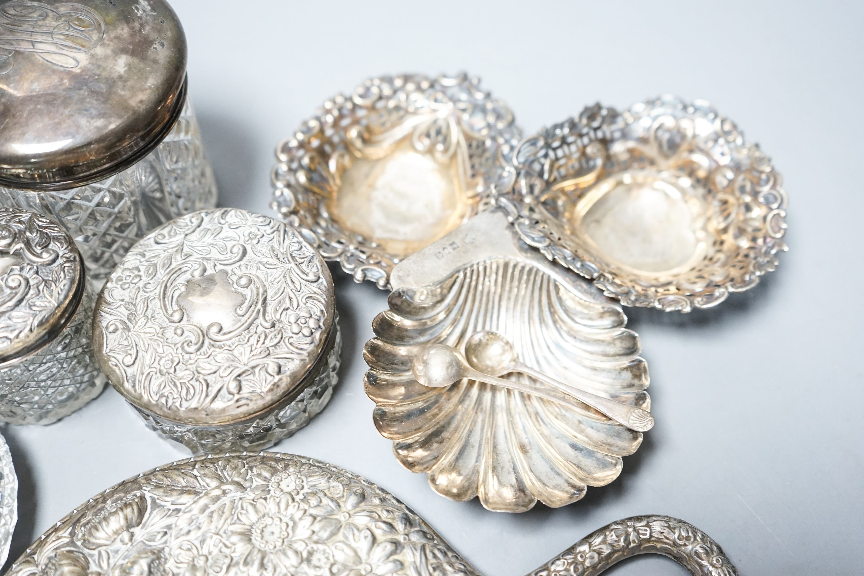 A silver and enamel mounted glass toilet jar, four other toilet jars, a hand mirror and three small silver dishes.